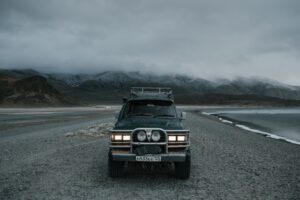 car-parked-on-seashore-near-mountains-in-foggy-weather-4328298